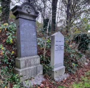 Two monuments each with a cross with a red Scottish poppy in front of them. Autumn leaves lie in front of both monuments.